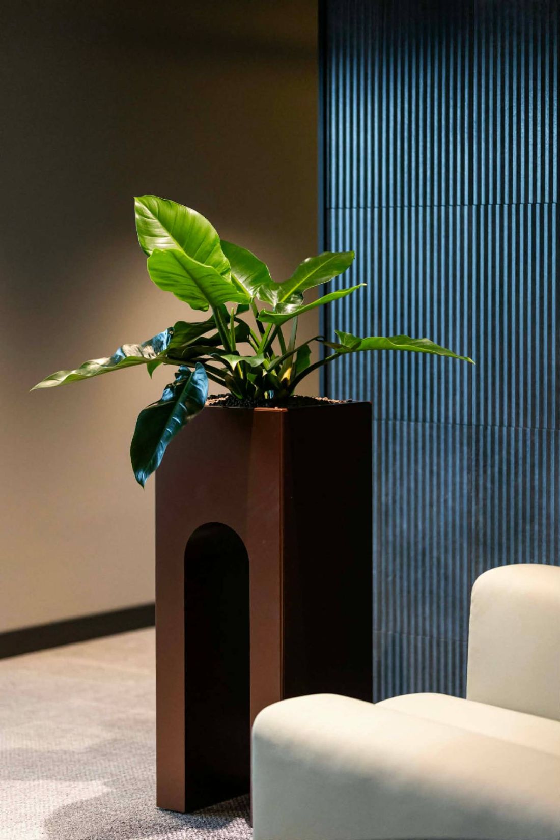 A Tower Bridge planter with its arched base, planted and installed against a fluted panel wall in a lounge interior